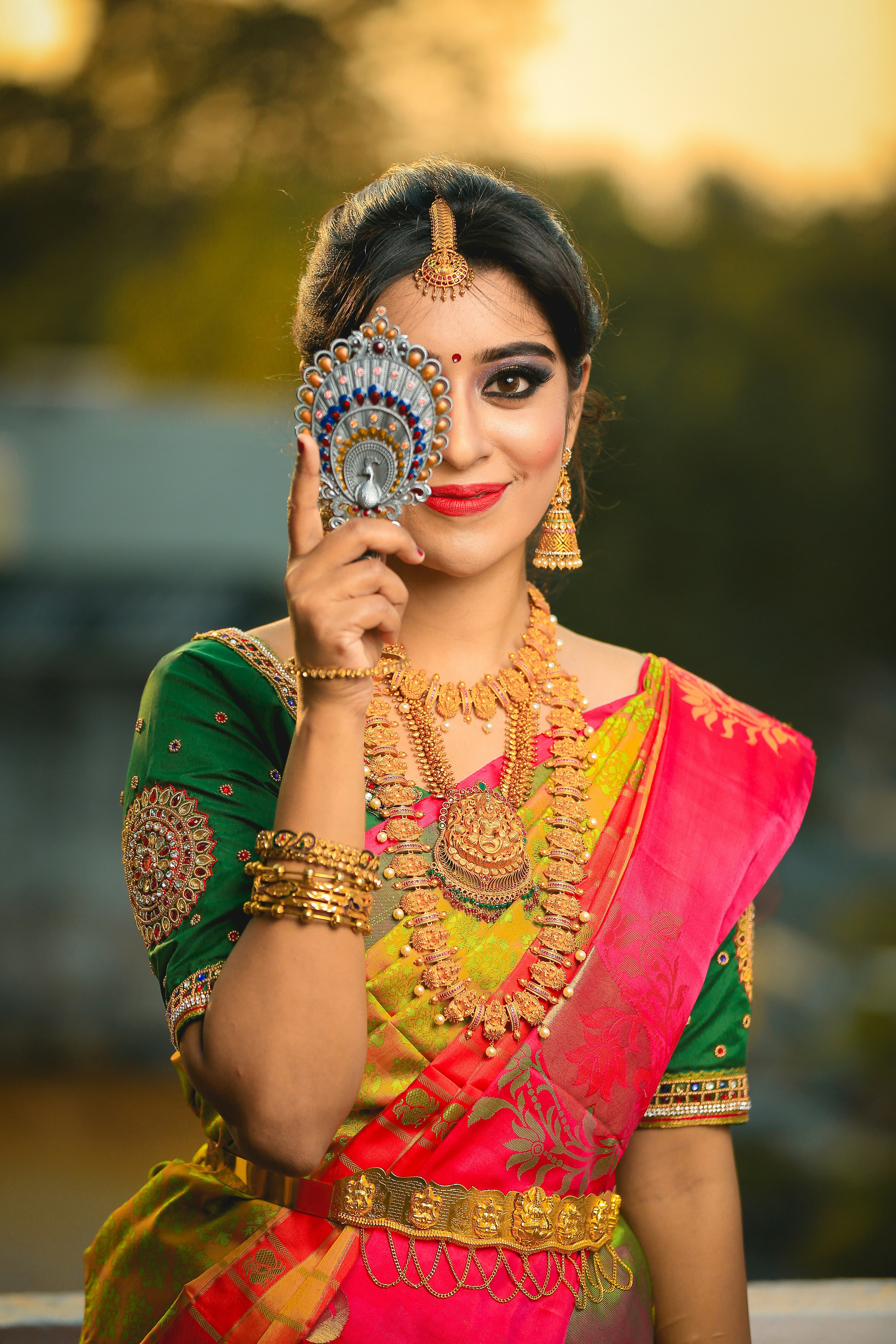 Bride in saree with jewelry holding mirror